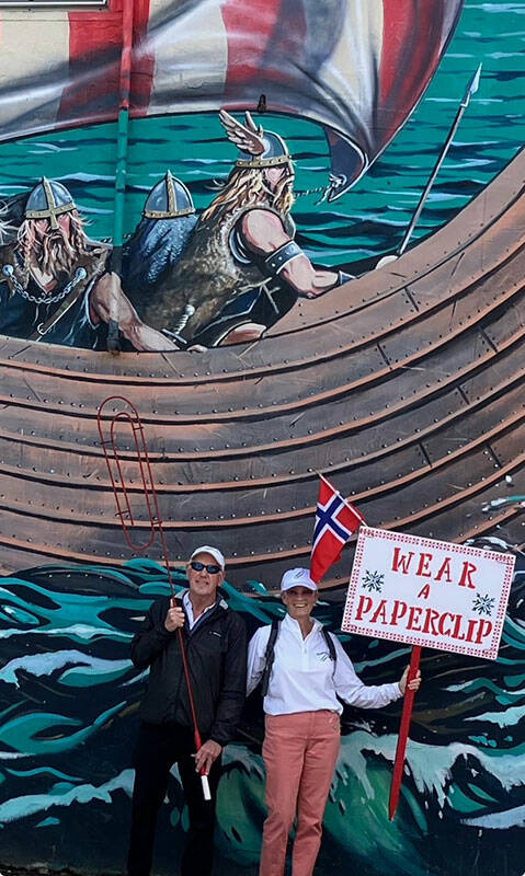 The Pedersens pose with their paperclip gear in front of the Viking mural in downtown Poulsbo during a rally in April.