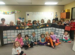 Students in the EL VELERO Spanish Immersion Program at Ordway Elementary School gather around a roll-out banner birthday card they made for for George Scott.