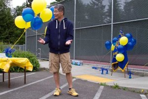 Long-time BHS varsity tennis team Assistant Coach Uly Cheng addresses the crowd gathered for the dedication of a memorial plaque for the team’s former Head Coach Mike Anderson at the school’s courts last week. Anderson passed away in September in a tragic drowning accident.