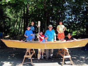 Tim Young stands with his young boat builders and their canoe.