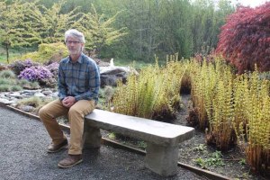 Grace Episcopal Church Rector Bill Harper sits near a garden on church grounds. Harper