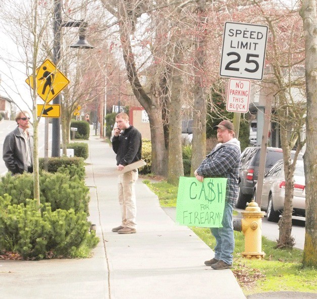 Area firearm enthusiasts wait outside the Bainbridge Island police station on Winslow Way offering cash for guns that would otherwise be turned in to the department.