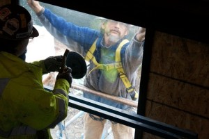 Construction workers with PHC construction carefully install the first pane of glass in the “Beacon” at the Bainbridge Island Museum of Art.