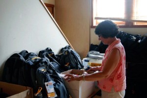 Marilyn Gremse looks through a box of glue sticks ready to be packed in backpacks for Helpline House's Project Backpack.