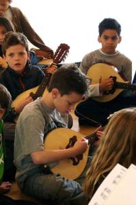 Second- and third-graders play mandolins with instruction from Zupf Duo