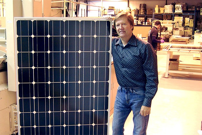 Itek Energy manufactures solar panels in Belllingham. Company President John Flanagan stands next to a panel similar to the ones that will be installed on the roof of city hall.