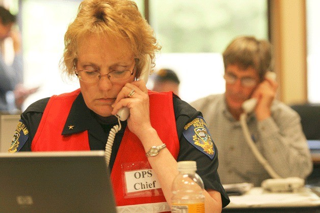 Bainbridge Police Cmdr. Sue Shultz fields a phone call during the Evergreen Quake 2012 drill Tuesday at the Bainbridge Island Fire Department's Emergency Operation Center.