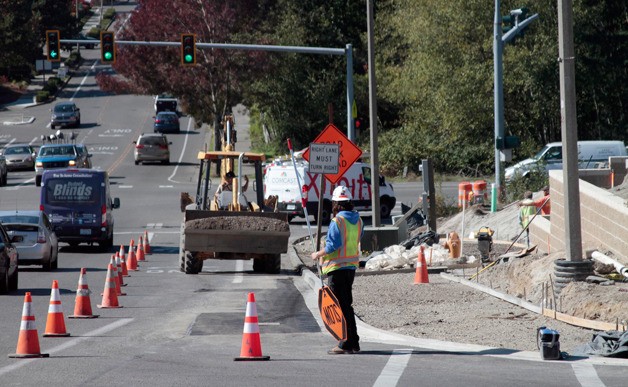 Work crews at the new shopping development on High School Road prep the area along the roadway for new sidewalks last week. A Walgreens official said the new drugstore at the site will open next month.