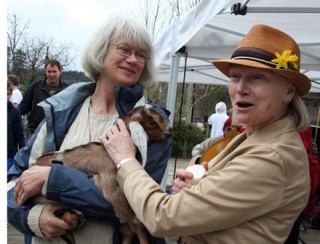 Mayor Darlene Kordonowy (right) pets a young goat held by Beverly Phillips of the Port Madison Goat Farm and Dairy
