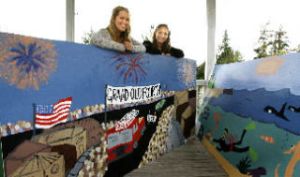 Laurel Curran (left) and Isabel Williams pose with their murals.