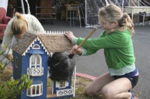 Volunteer Marielle Summers dusts off a custom-made dollhouse during setup for this weekend’s Rotary Auction and Rummage Sale at Woodward Middle School.