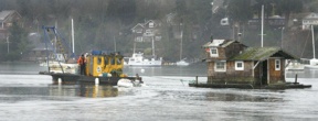 The ailing houseboat Wicca is towed out of Eagle Harbor by a Caicos tug Thursday morning. Historic preservationists hope the floating home