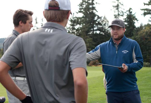 Spartan Head Coach Austin Hurt hands out scorecards prior to the start of the Bainbridge High boys varsity golf team’s match against visiting O’Dea.