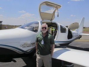Harry Anderson stands in front of the single-engine Columbia Lancair airplane that he flew around the world in.