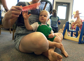 A quick snuggle in mom’s lap provides quiet time play for 15-month-old Connor LaCroix. Connor and his mom