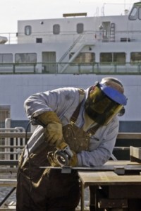 Welder Gary West buffs a part at the downtown Winslow ferry maintenance yard.