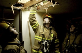 Firefighter Mike Spray checks out the ventilation cut into the roof of a home donated for fire training.