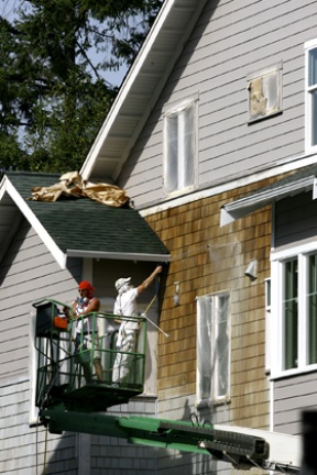 Construction workers power wash siding recently at Madrone Village on Winslow Way. The 38-unit project will be finished in December.