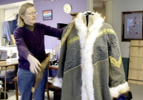 Barbara Klingberg drapes trim over a coat for the “Spirit of Christmas Present