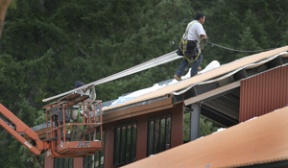 Workers install metal roofing on one of the 11 buildings at the new business complex off of Sportsman Club road.