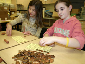 Sakai fifth-graders Sarah Dacquisto and Rachel Kaminer tally up coins for the Coins That Care tsunami relief fund.