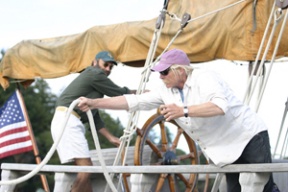 Islander and captain Roger Katz (at top) turns the ship’s wheel as engineer Bruce Tipton throws a line to a passerby as the 1913 schooner Ragland puts in at Waterfront Park on Tuesday. The vessel