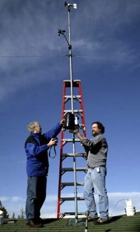 Sakai Intermediate School science teacher Doug Olson (left) and Bainbridge Island School District technical support specialist Price Court finishes mounting the new weather station atop Woodward Middle School Thursday.