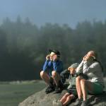 Brian Kelly | Bainbridge Island Review                                Tamra Hauge (far right) watches the eclipse with her sons Magnus and Alden from the perch of a big rock at Manitou Beach.