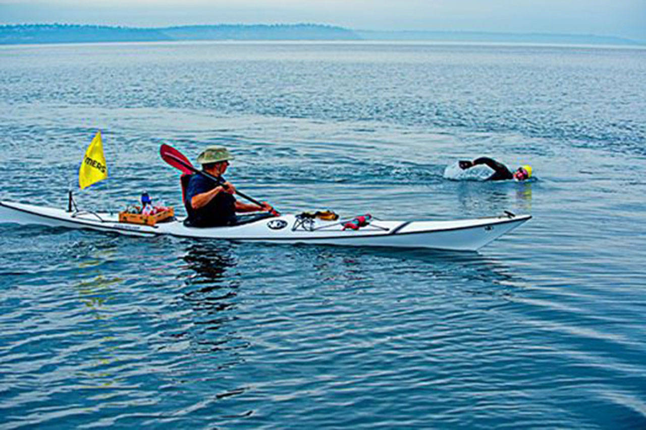 Photo courtesy of Pete Saloutos.                                Michael Silves kayaks behind John Goessman during a round-the-island swim in 2014.