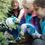 Tami Allen, Elle Perkins and Hannah Rudnick clean up styrofoam nurdles after crawling into dense undergrowth at Hawley Cove Park. (Nick Twietmeyer | The Bainbridge Island Review)