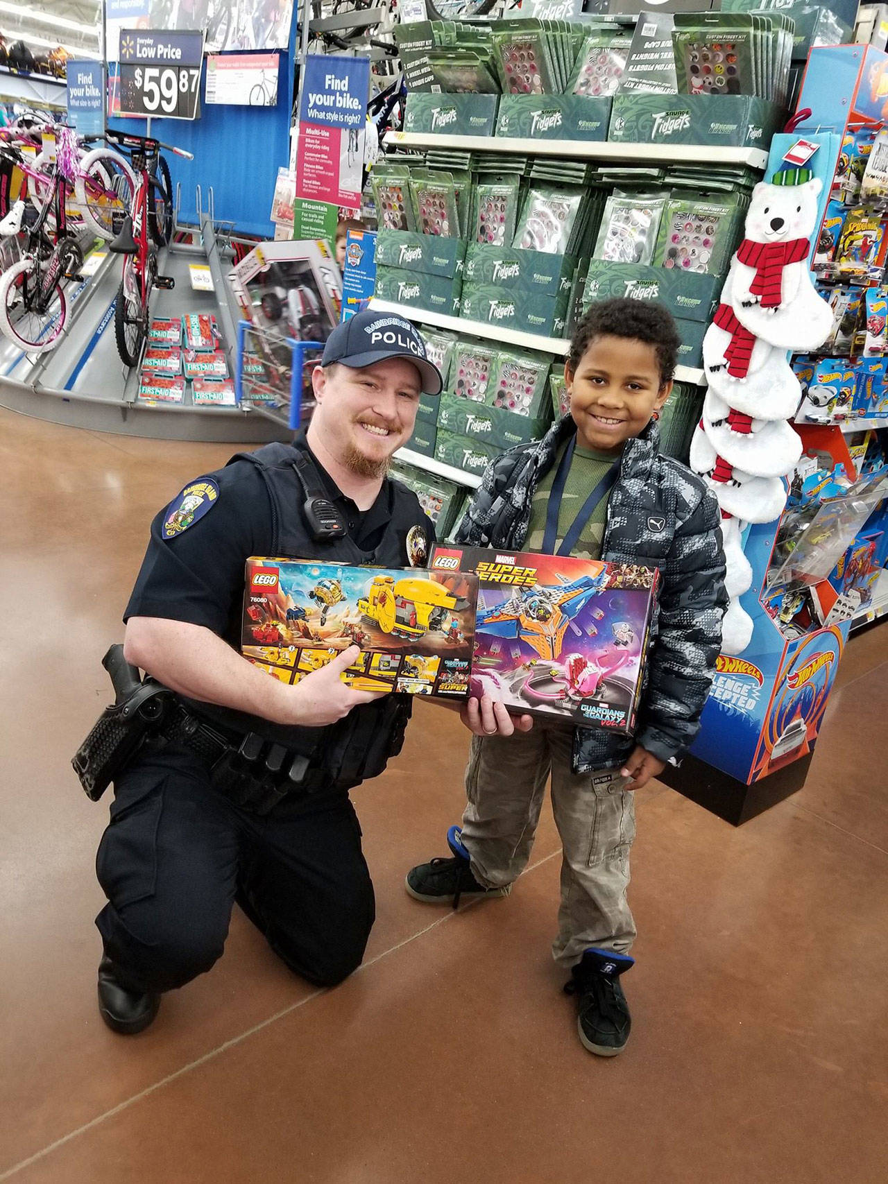 Bainbridge Police Officer Chuck Kazer helps shopper Emmanuel Rivas, 9. (Photo courtesy of the Bainbridge Island Police Department)