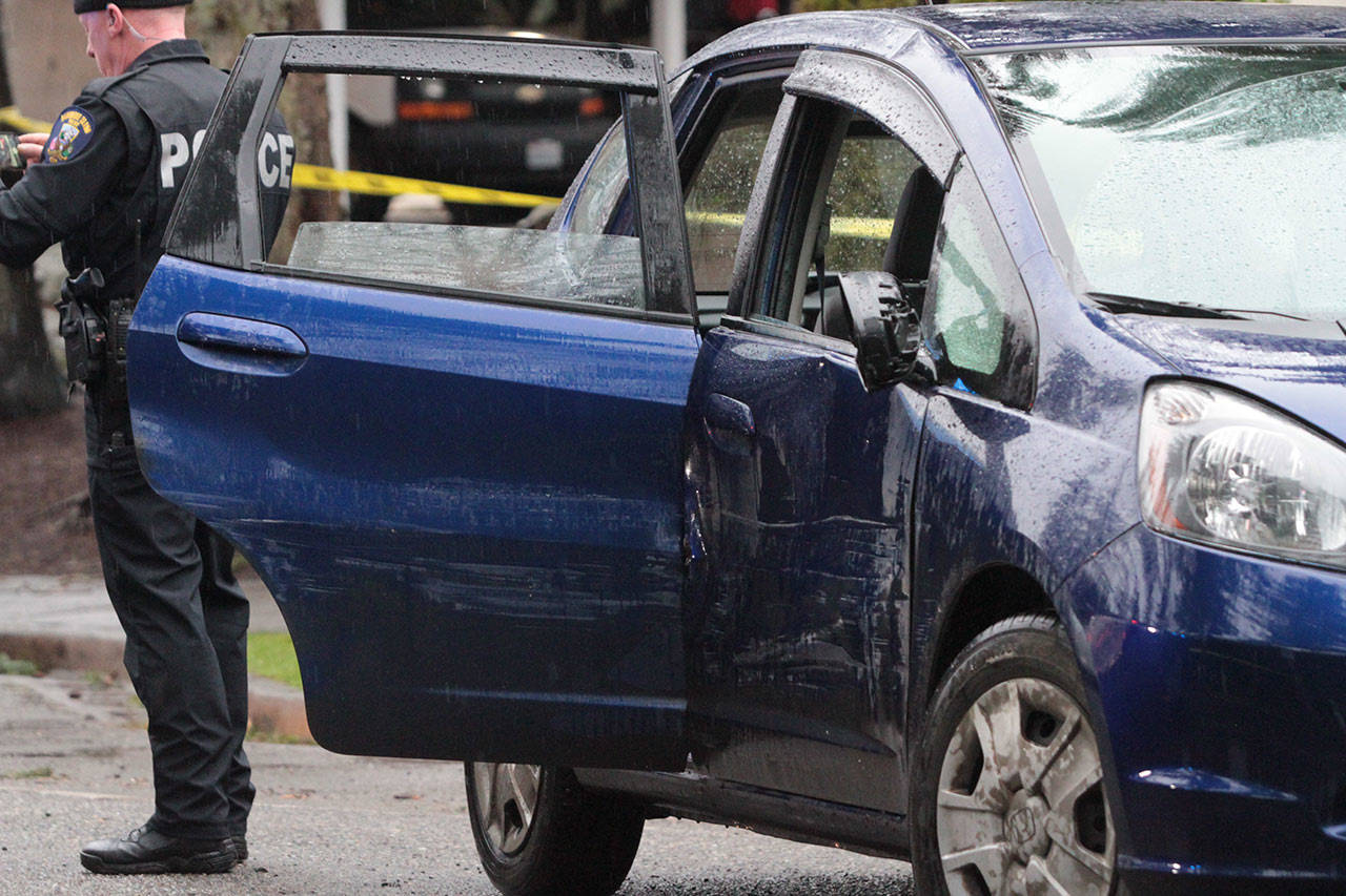 An officer stands next to the car that was driven by a man they say entered Bainbridge High Wednesday and assaulted students. The fleeing suspect was stopped after police rammed his vehicle on Wyatt Way.