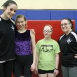 Gymnasts Tate Goff and Keara Callahan, center, stand with Bainbridge High gymnast and mentor Emma Chee and Bainbridge Island Gymnastics Club Coach Kendra Aquiningoc after a recent practice . (Brian Kelly | Bainbridge Island Review)