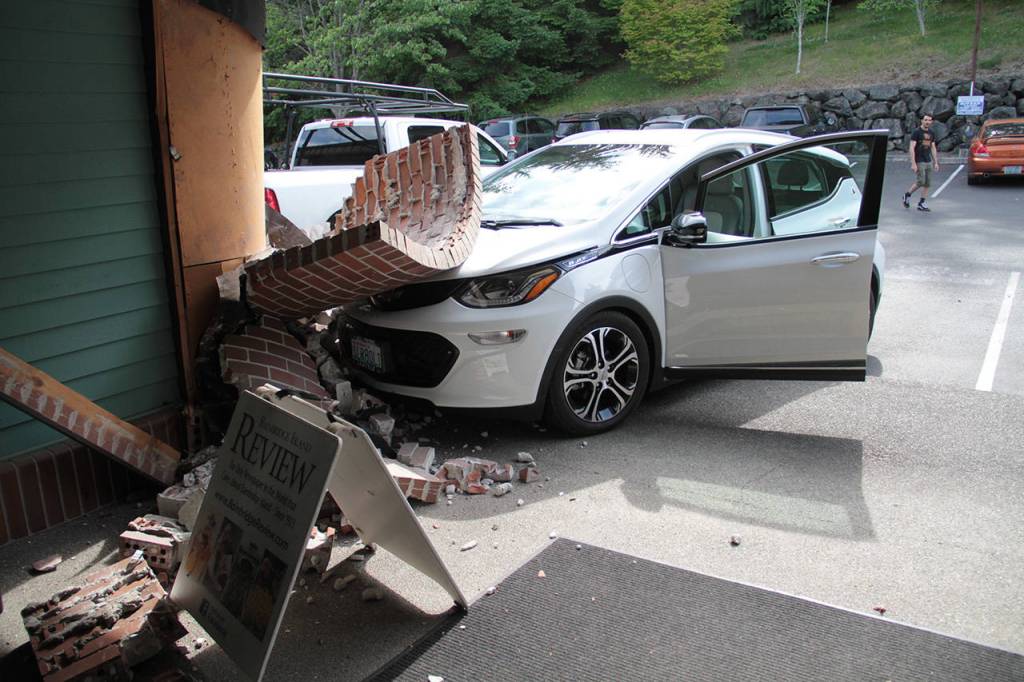 Part of the facade of the 911 Hildebrand Building rests on the hood of a Chevrolet Bolt EV after it crashed into the building. (Brian Kelly | Bainbridge Island Review)