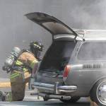A Bainbridge Island firefighter kneels next to a Volkswagen Squareback station wagon that caught fire Monday in the parking lot of the Island Village Shopping Center. (Brian Kelly | Bainbridge Island Review)