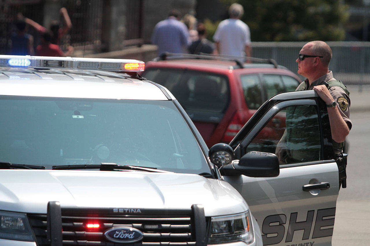Kitsap County Sheriff Deputy J. Childs waits at the corner of Winslow Way and Madison Avenue as police search for a robbery suspect Saturday. (Brian Kelly | Bainbridge Island Review)