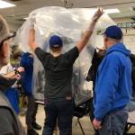 Bainbridge High students put their new robot, CHAOS, under a protective bag. CHAOS will meet the island community at an open house Wednesday, March 13 at BHS, where members of the 4915 Spartronics, the schools robotics team, will show off their latest creation. (Photo courtesy of 4915 Spartronics)