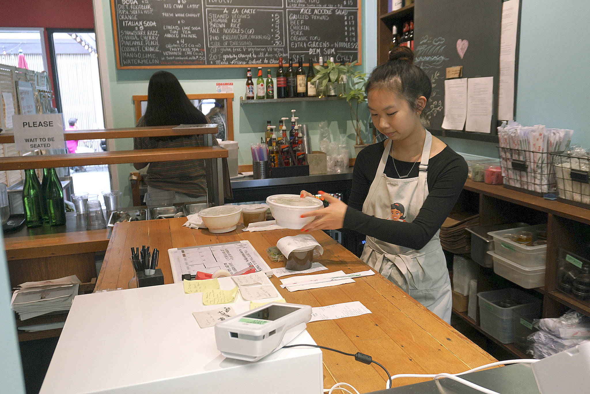 Luciano Marano | Bainbridge Island Review - Thuys Pho House has occupied several spaces around Winslow throughout the past decade, but the new location on Madrone Lane offers both indoor and outdoor seating as well as a pick-up window for to-go orders.                                 Luciano Marano | Bainbridge Island Review - A server packs a to-go order at the front window at the new location of Thuys the former location of Fork & Spoon (120 Madrone Lane North).