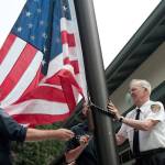 Luciano Marano | Bainbridge Island Review - Bainbridge Island Fire Department Assistant Chief Chuck Callaham (right), who has been with the department, serving in various capacities, since 1951, conducted the inaugural flag raising at the newly rebuilt Station 22 Monday, Aug. 12.