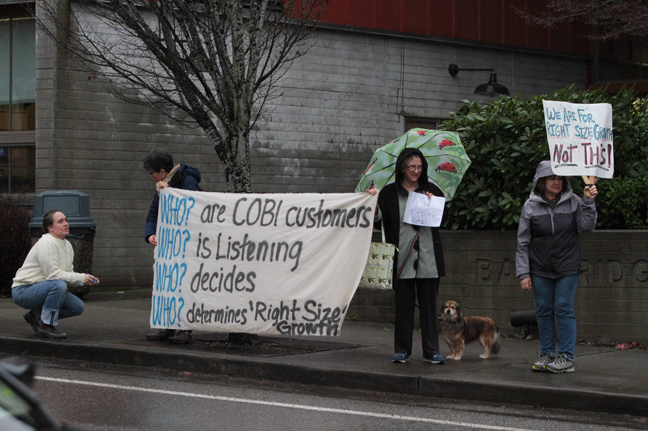 A small group of demonstrators gather outside Bainbridge Island City Hall before the start of Thursdays public hearing on the Winslow Hotel. (Brian Kelly | Bainbridge Island Review)