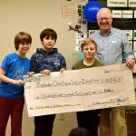 Three fifth-grade students present a check from their calendar sales to Paul Carroll of Bainbridge Ometepe Sister Islands Association. (Photo courtesy of The Island Schoo)
