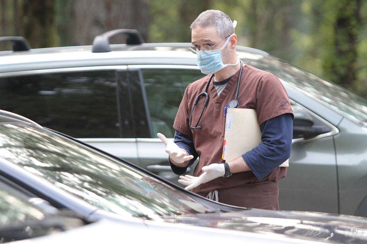 Veterinarian Mark Swaney talks with a dog owner in the parking lot of the Day Road Animal Hospital. (Brian Kelly | Bainbridge Island Review)