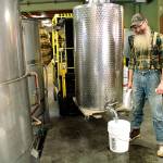 Kevin Barrans, head distiller at Bainbridge Organic Distillers, fills a five-gallon bucket with alcohol taht was made at the Bainbridge business. Buckets of alcohol will be donated to Bainbridge Prepares so it can be made into hand sanitizer. (Brian Kelly | Bainbridge Island Review)