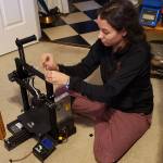 Spartronics leadership team member Merrill Keating uses a 3D printer she assembled during Spring Break to print ear protectors for masks being made for health care professionals and first responders. (Photo courtesy of Enrique Chee)