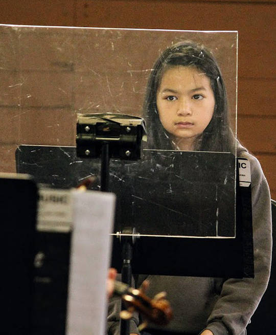 Musicians who play brass or woodwinds without masks perform behind plastic shields.