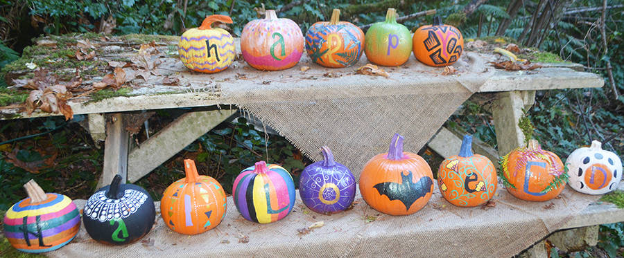 This group of pumpkins spells out "Happy Halloween" on a picnic table.