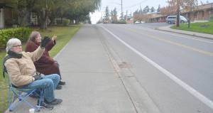 Caregiver Scott McDonald and Vickie Helsi wave to cars as they go by. Steve Powell/Bainbridge Island Review photograph