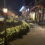 The sidewalks are lit up at night with decorations.