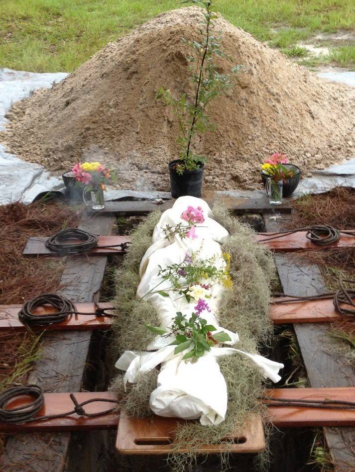 Remains wrapped in linen shroud with cedar planks below.