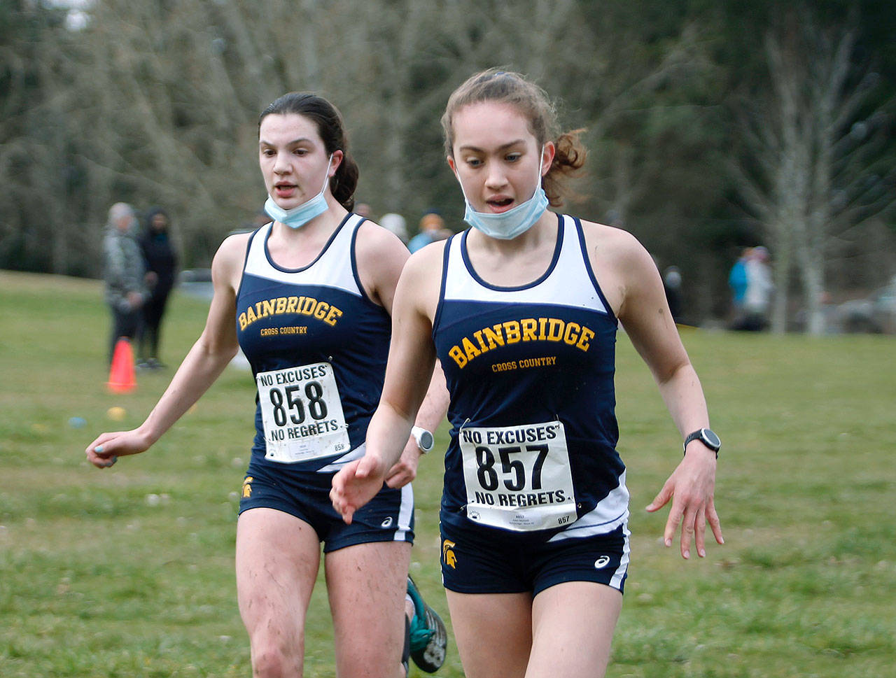 Bainbridge runners Lucy King (left) and Eden Michael (right) cross the finish line in the final regular season Olympic League meet at Battle Point Park against Bremerton. (Mark Krulish/Kitsap News Group)